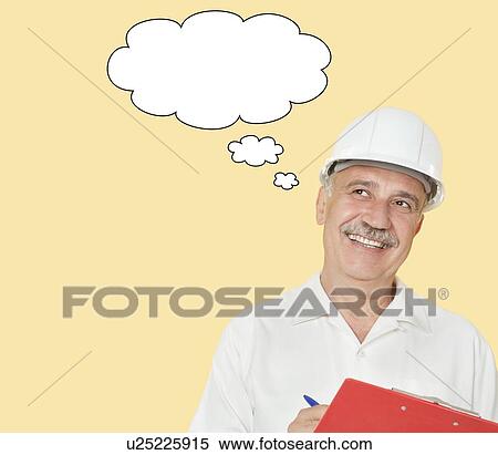 Stock Photography - Senior constructor with clipboard looking away over yellow background. Fotosearch