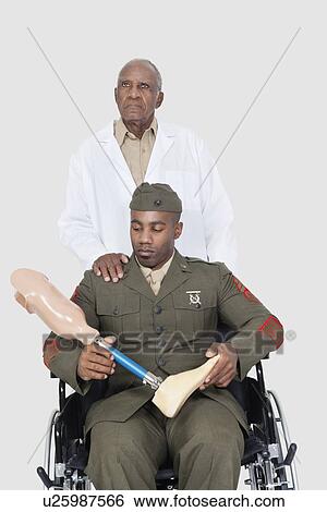 Senior doctor with US military officer holding artificial limb as he sits in wheelchair over gray background View Large Photo Image Stock Photograph - Senior doctor with US military officer holding artificial limb as he sits in wheelchair over gray background. Fotosearch