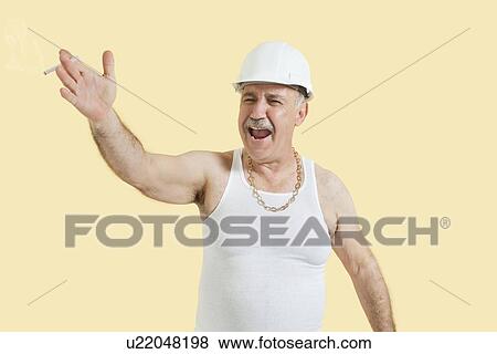 Stock Photo - Senior male constructor shouting over yellow background. Fotosearch