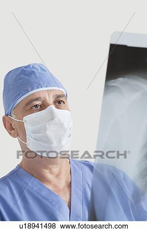 Senior male surgeon examining x-ray over gray background View Large Photo Image Stock Photo - Senior male surgeon examining x-ray over gray background. Fotosearch