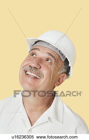 Senior man with hardhat looking up and smiling over yellow background View Large Photo Image Stock Photography - Senior man with hardhat looking up and smiling over yellow background. Fotosearch