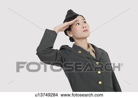 Serious female US military officer saluting over gray background View Large Photo Image Picture - Serious female US military officer saluting over gray background. Fotosearch