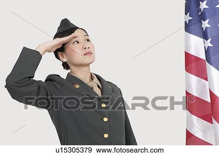 Serious female US military officer saluting American flag over gray background View Large Photo Image Stock Photo - Serious female US military officer saluting American flag over gray background. Fotosearch