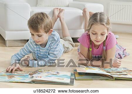 Siblings reading story books on floor in the living room View Large Photo Image Stock Image - Siblings reading story books on floor in the living room. Fotosearch