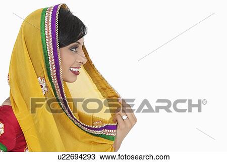 Stock Image - Side view of Indian female holding dupatta over white background. Fotosearch