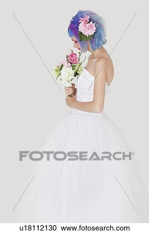 Stock Image - Side view of young woman in wedding dress with dyed hair against gray background. Fotosearch