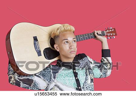Teenage boy carrying guitar over his shoulder over pink background View Large Photo Image Stock Photography - Teenage boy carrying guitar over his shoulder over pink background. Fotosearch