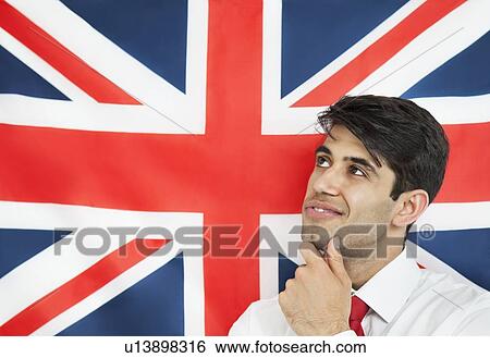 Stock Photograph - Thoughtful young man with hand on chin against British flag. Fotosearch