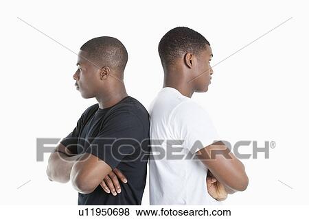 Two male friends standing back to back over gray background View Large Photo Image Stock Photo - Two male friends standing back to back over gray background. Fotosearch