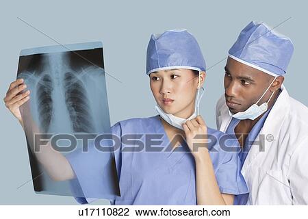 Two surgeons examining x-ray report over light blue background View Large Photo Image Stock Image - Two surgeons examining x-ray report over light blue background. Fotosearch