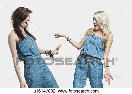 Two surprised women wearing similar jump suits looking at each other over gray background View Large Photo Image Stock Image - Two surprised women wearing similar jump suits looking at each other over gray background. Fotosearch