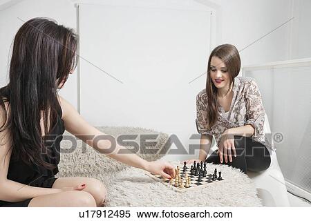 Two young female friends playing chess View Large Photo Image Stock Photography - Two young female friends playing chess. Fotosearch