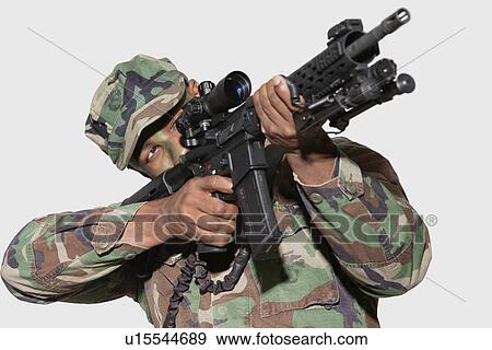 Stock Photo - US Marine Corps soldier aiming M4 assault rifle against gray background. Fotosearch
