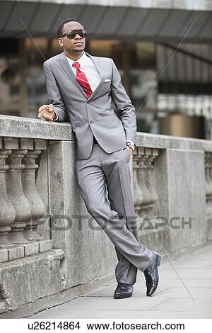 Young African American businessman leaning against wall View Large Photo Image Picture - Young African American businessman leaning against wall. Fotosearch