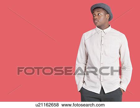 Stock Photo - Young African American man looking sideways over red background. Fotosearch
