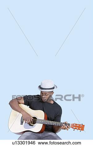 Young African American man playing guitar over light blue background View Large Photo Image Stock Photograph - Young African American man playing guitar over light blue background. Fotosearch