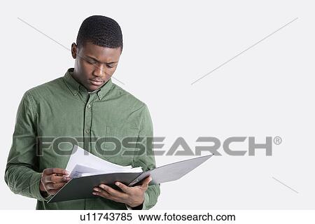 Stock Photography - Young African American man reading documents over gray background. Fotosearch