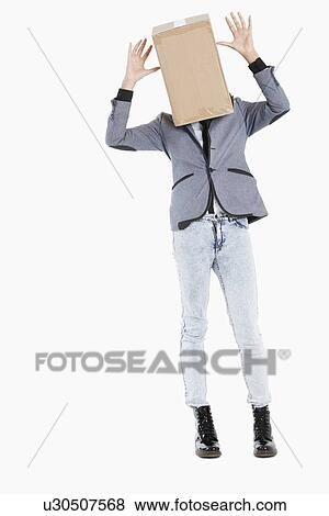 Stock Photo - Young boy with box covered over his face and hands raised over gray background. Fotosearch