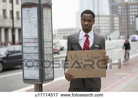 Young businessman holding "Will Work for Food" sign at street View Large Photo Image Stock Photo - Young businessman holding "Will Work for Food" sign at street. Fotosearch