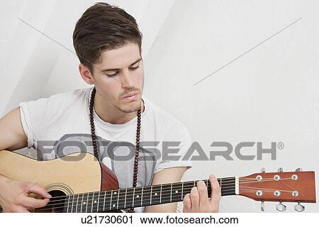 Stock Image - Young Caucasian man playing guitar. Fotosearch
