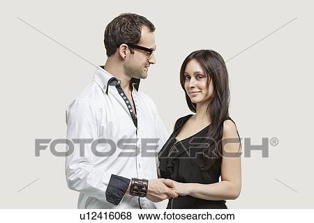 Stock Photo - Young couple holding hands against gray background. Fotosearch