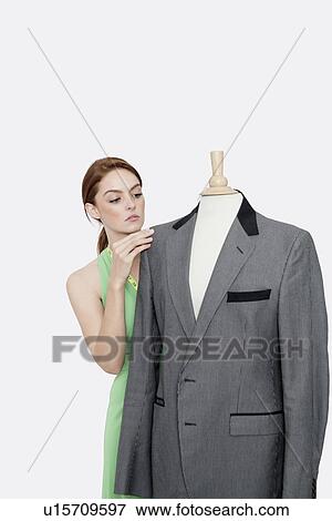 Young female fashion designer looking at blazer on tailor's dummy over gray background View Large Photo Image Stock Photo - Young female fashion designer looking at blazer on tailor's dummy over gray background. Fotosearch