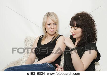 Young female friends sitting on sofa and talking View Large Photo Image Picture - Young female friends sitting on sofa and talking. Fotosearch