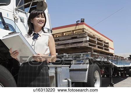 Young female holding clipboard while standing next to flatbed truck View Large Photo Image Stock Image - Young female holding clipboard while standing next to flatbed truck. Fotosearch