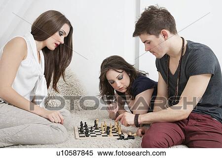 Stock Photography - Young friends playing chess on sofa. Fotosearch