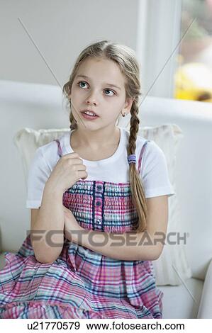 Young girl thinking while sitting on sofa View Large Photo Image Stock Photo - Young girl thinking while sitting on sofa. Fotosearch