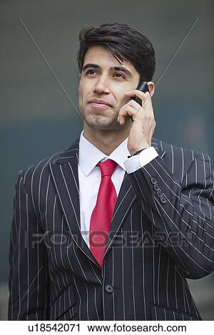 Stock Image - Young Indian businessman communicating on cell phone. Fotosearch