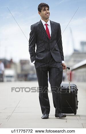 Young Indian businessman pulling luggage bag on street View Large Photo Image Stock Image - Young Indian businessman pulling luggage bag on street. Fotosearch