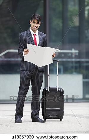 Young Indian businessman with luggage bag reading paper View Large Photo Image Stock Image - Young Indian businessman with luggage bag reading paper. Fotosearch