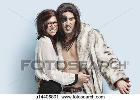 Young man in fur coat sticking out tongue while standing with happy woman against light blue background View Large Photo Image Stock Image - Young man in fur coat sticking out tongue while standing with happy woman against light blue background. Fotosearch