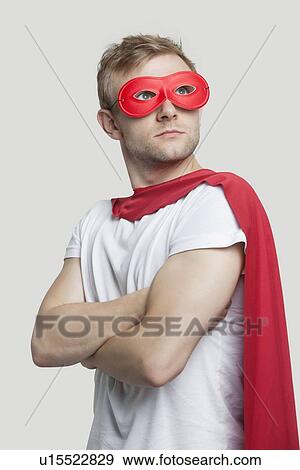 Stock Photo - Young man in red superhero costume looking up over gray background. Fotosearch