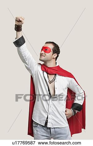 Young man in superhero costume standing against gray background View Large Photo Image Stock Photo - Young man in superhero costume standing against gray background. Fotosearch