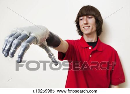 Stock Photography - Young man looking at his prosthetic hand over gray background. Fotosearch
