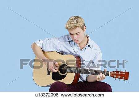 Young man playing guitar over blue background View Large Photo Image Stock Photograph - Young man playing guitar over blue background. Fotosearch
