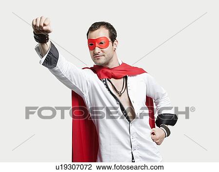 Young man wearing superhero costume against gray background View Large Photo Image Stock Image - Young man wearing superhero costume against gray background. Fotosearch