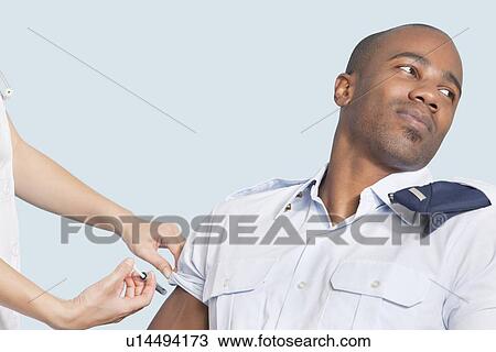 Young military man looking away as being injected by nurse over light blue background View Large Photo Image Stock Image - Young military man looking away as being injected by nurse over light blue background. Fotosearch