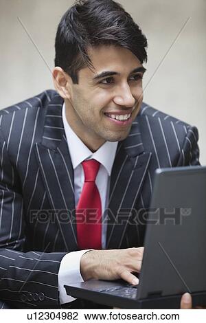 Young smiling Indian businessman using laptop View Large Photo Image Stock Image - Young smiling Indian businessman using laptop. Fotosearch