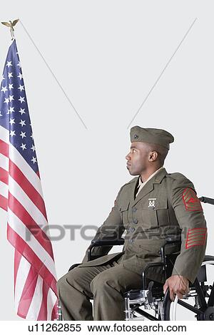 Young US soldier in wheelchair looking at American flag over gray background View Large Photo Image Stock Photography - Young US soldier in wheelchair looking at American flag over gray background. Fotosearch