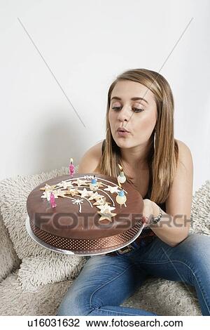 Young woman blowing out candles on birthday cake View Large Photo Image Stock Image - Young woman blowing out candles on birthday cake. Fotosearch