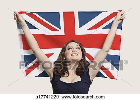 Stock Photo - Young woman holding British Flag with pride over gray background. Fotosearch