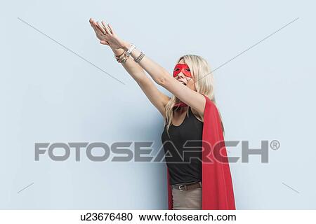 Young woman in superhero outfit pretending to leap in the air against light blue background View Large Photo Image Stock Image - Young woman in superhero outfit pretending to leap in the air against light blue background. Fotosearch