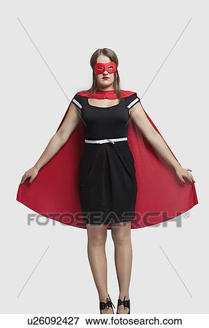 Young woman standing in superhero costume over gray background View Large Photo Image Stock Photo - Young woman standing in superhero costume over gray background. Fotosearch
