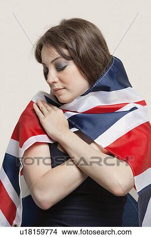 Picture - Young woman wrapped in British Flag over gray background. Fotosearch