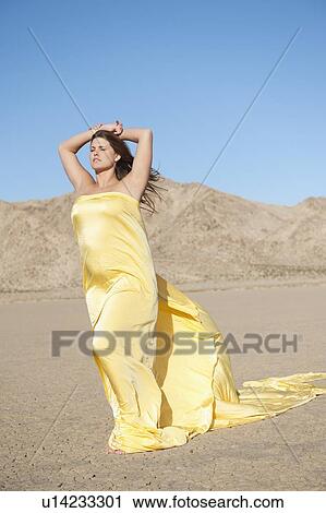 Young woman wrapped in yellow cloth on arid landscape View Large Photo Image Stock Image - Young woman wrapped in yellow cloth on arid landscape. Fotosearch