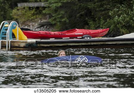 Stock Photography - Girl falling into the lake during surfboarding, Lake of the Woods, Ontario, Canada. Fotosearch