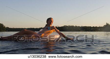 Stock Photo - Girl in a inflatable ring floating on water, Lake of the Woods, Ontario, Canada. Fotosearch